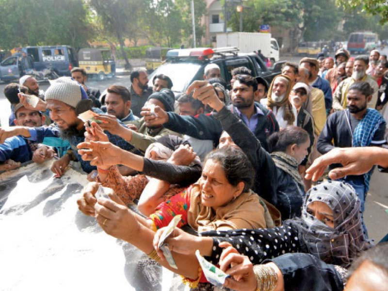 people made to stand in queue by a police mobile squad hold cash in hands to buy subsidised flour bags at a sale point in karachi the officials selling flour strictly ordered one person one bag only photo express