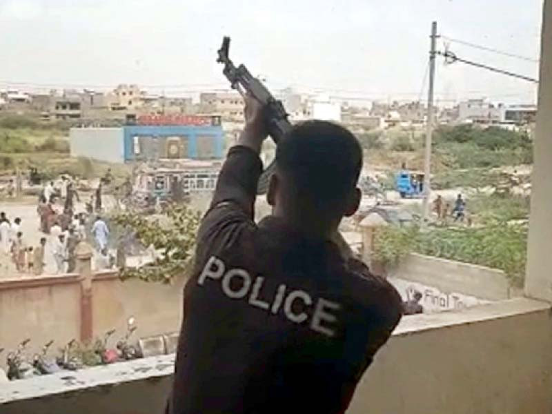 a policeman fires in the air to scare away protestors that had gathered outside the surjani police station photo express