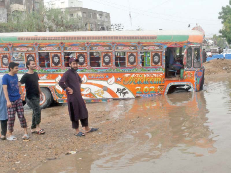 a bus is stuck in a crater formed after friday s downpour due to unfinished roadwork near nagan chowrangi in central district photo online