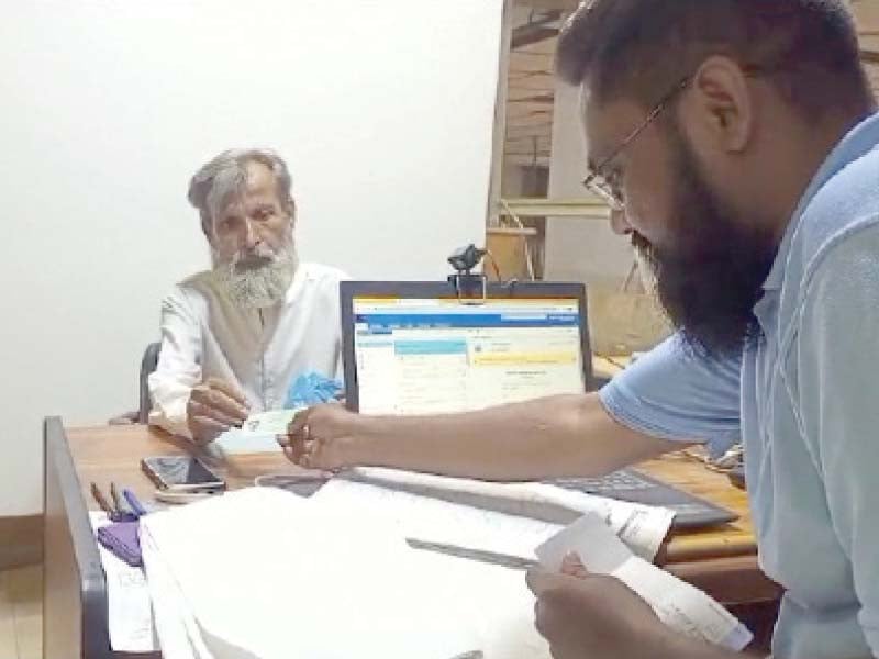 an elderly man gets his cnic renewed at a post office photo express