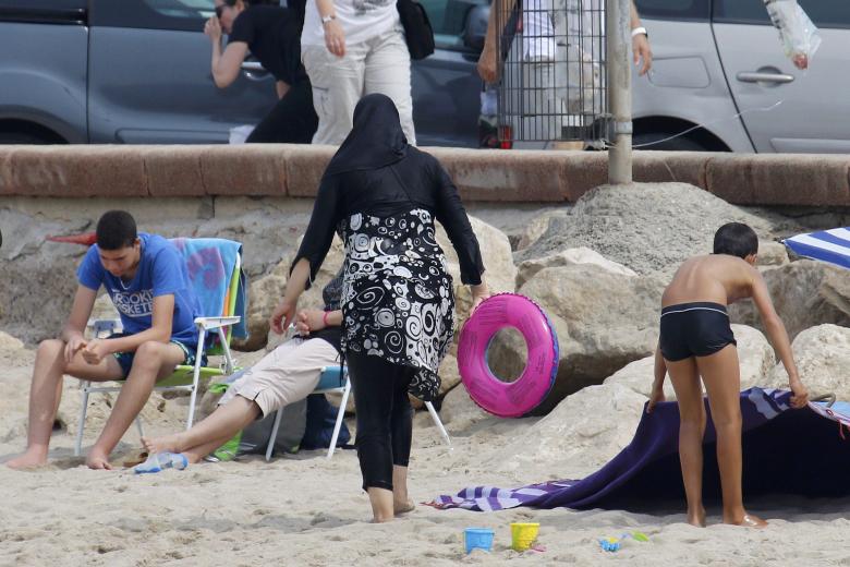 a muslim woman wears a burkini a swimsuit that leaves only the face hands and feet exposed on a beach in marseille photo reuters