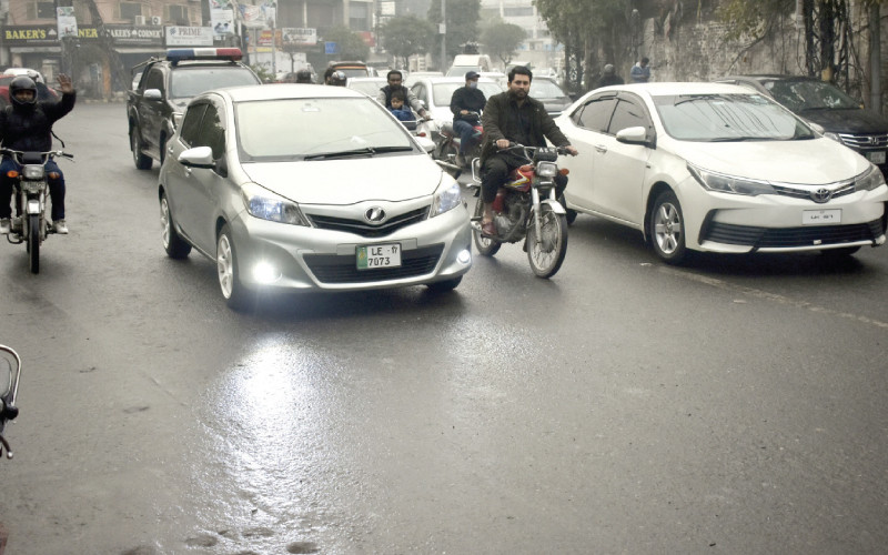 motorists on their way during a drizzle induced artificially in a part of lahore photo online