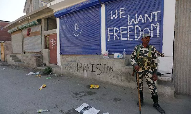 a policeman stands guard near shops painted with graffiti during a curfew in srinagar photo rueters a policeman stands guard near shops painted with graffiti during a curfew in srinagar photo rueters