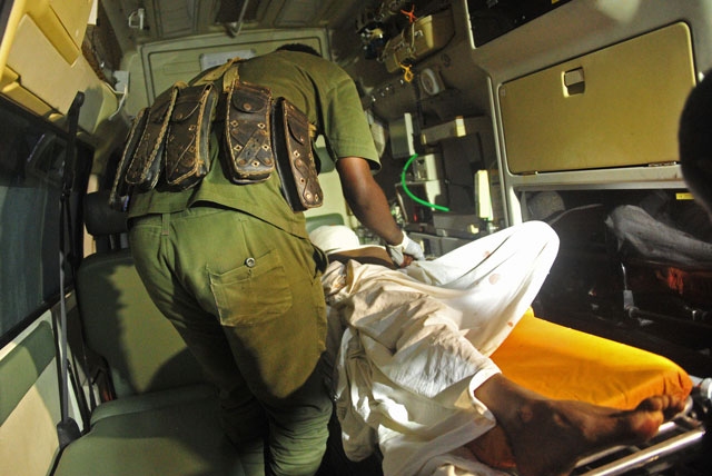 a somalian soldier l stands guard by a wounded alleged al qaeda linked shebab rebel in an ambulance at daru shifa hospital in somali capital mogadishu on august 25 2016 photo afp