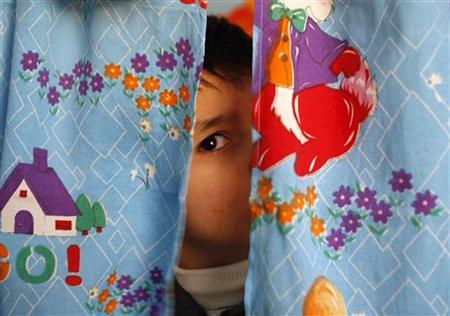 an autistic child peers from between curtains at the consulting centre for autism in amman jordan photo reuters