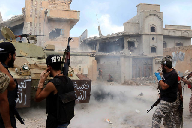 a member of the forces loyal to libya 039 s un backed government of national accord gna fires his rifle as others protect themselves behind a wall on august 28 2016 in the coastal city of sirte east of the capital tripoli during their military operation to clear the islamic state group 039 s is extremists from the city photo afp