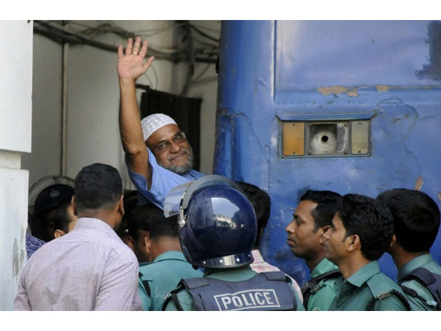 bangladeshi jamaat e islami party leader mir quasem ali waves as he enters a van at the international crimes tribunal court in dhaka in november 2014 photo afp