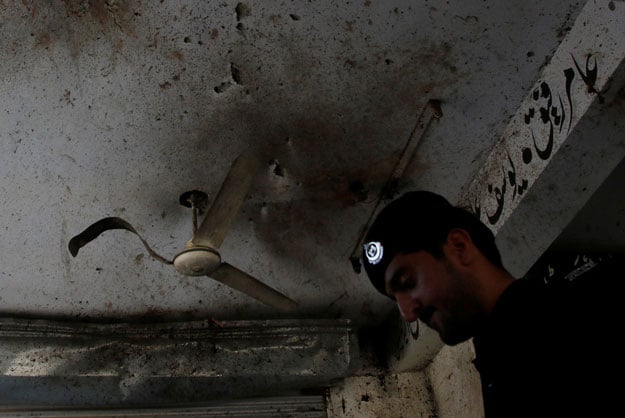 a policeman looks for evidence under a damaged ceiling after twin bomb attack occurred at a court in mardan september 2 2016 photo reuters