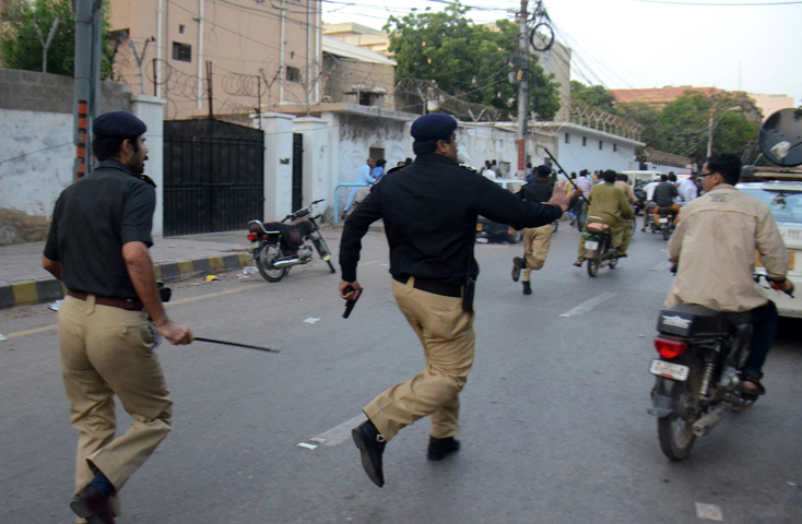 policemen chase activists from the muttahida qaumi movement mqm politicial party during a clash in karachi on august 22 2016 photo afp