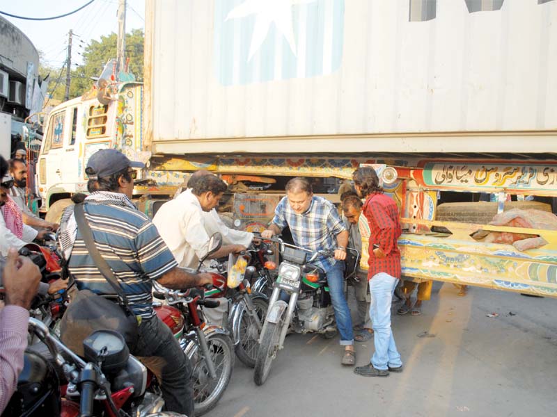 motorcyclists drive under a container placed on a road along the rally route photo abid nawaz express