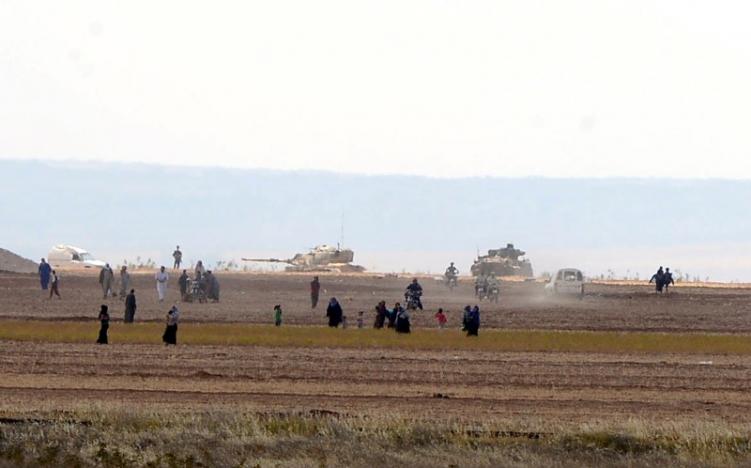 syrian civilians with turkish army tanks in the background walk through the turkish border as they are pictured from a village in kilis province turkey september 3 2016 photo reuters