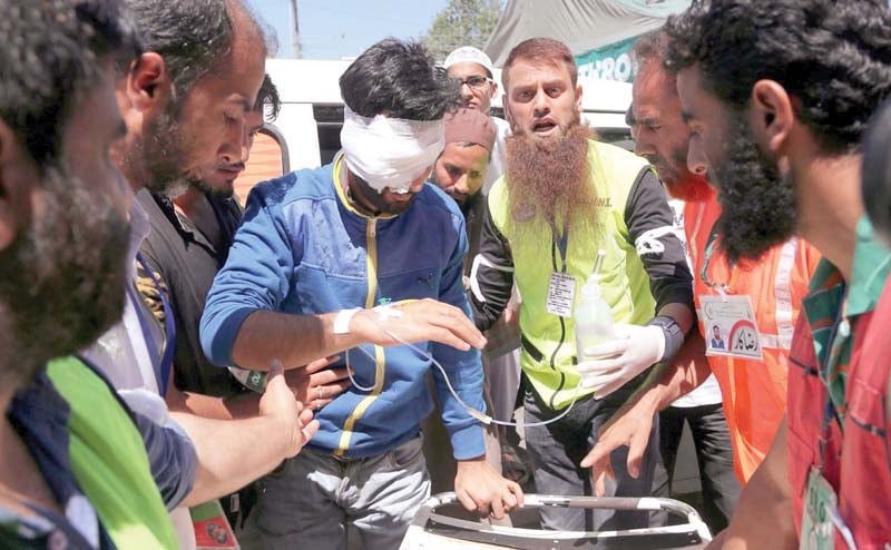 volunteers help a wounded man outside a hospital in indian kashmir photo inp