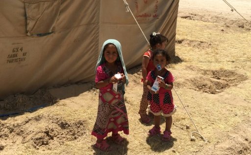 displaced iraqi children stand outside a tent at a camp southwest of baghdad in may 2016 photo afp