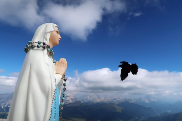 a mountain jackdaw flies past a little praying madonna statue on top of the piz boe mountain in the dolomites alpine region near arabba italy photo reuters