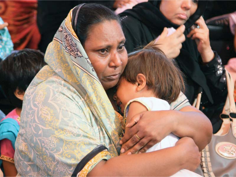 a woman who lost a relative in the factory fire grieves at the incident s anniversary in 2015 photo file