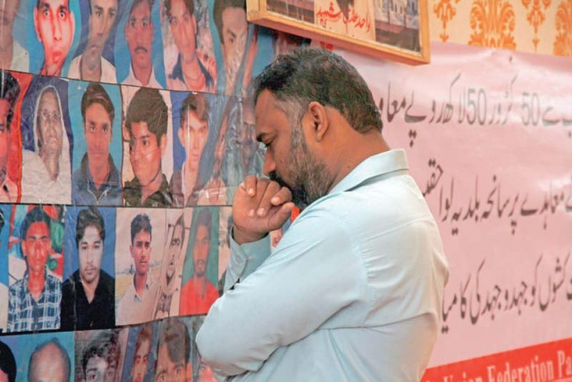 a man mourns his loved ones whose portraits have been put on the fourth anniversary of baldia factory fire photo athar khan express