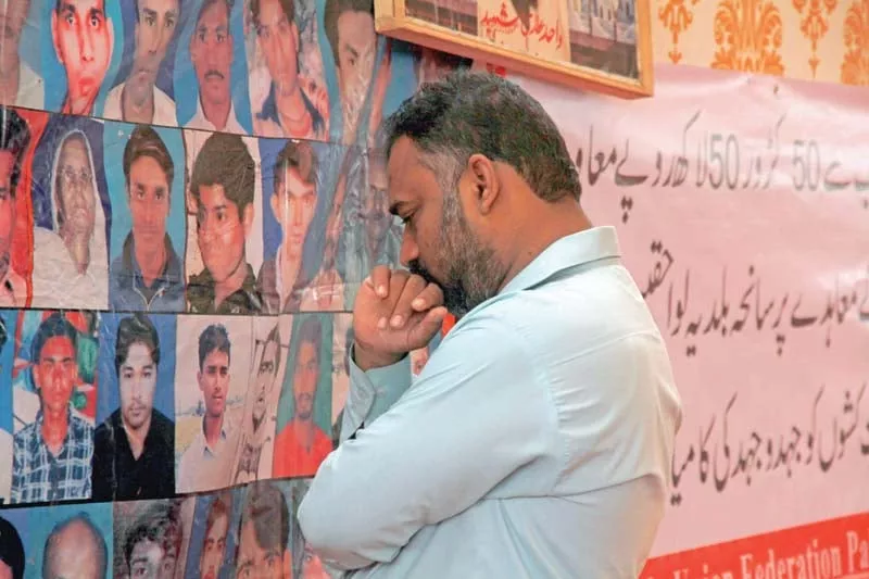 a man mourns his loved ones whose portraits have been put on the fourth anniversary of baldia factory fire photo athar khan express a man mourns his loved ones whose portraits have been put on the fourth anniversary of baldia factory fire photo athar khan express