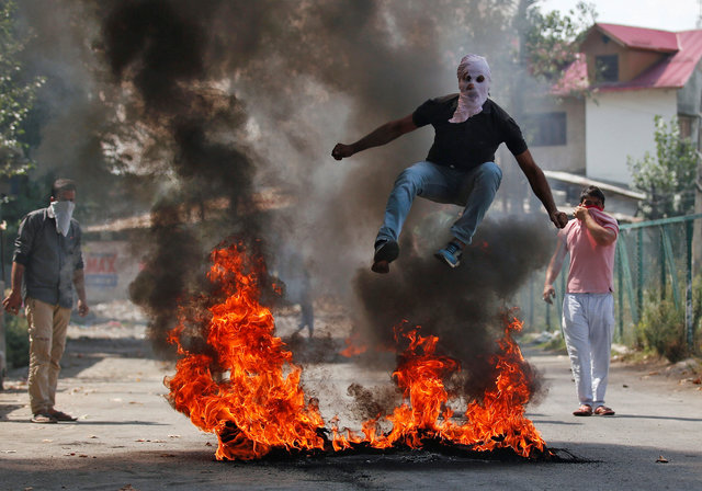 a man in a balaclava jumps over burning debris during a protest against the recent killings in kashmir in srinagar india september 12 2016 photo reuters