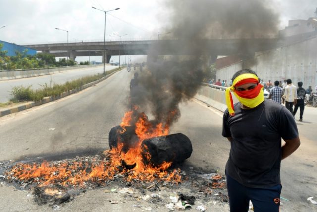 an indian activist stands beside a traffic blockade at a major connecting road during a protest in bangalore photo afp