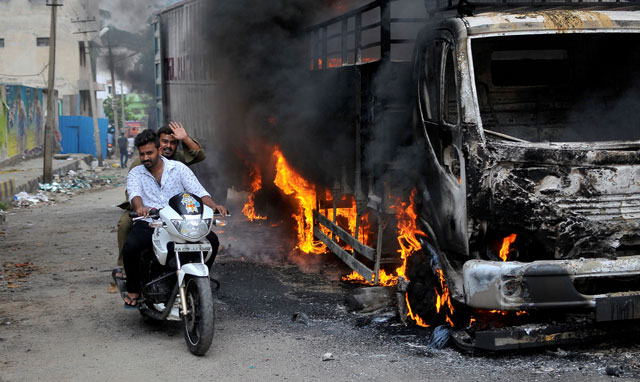 men ride a motorcycle past a lorry in bengaluru which was set on fire by protesters after india 039 s supreme court ordered karnataka state to release 12 000 cubic feet of water per second every day from the cauvery river to neighbouring tamil nadu india september 12 2016 photo reuters