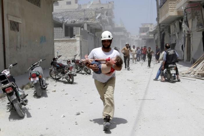 a civil defence member carries an injured girl at a site hit by airstrikes in the rebel controlled area of maaret al numan town in idlib province syria photo reuters