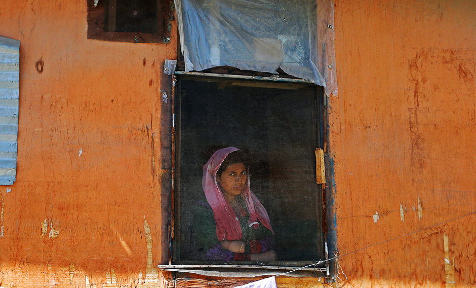 a woman looks out from a window during a protest against the recent killings in kashmir in srinagar photo reuters