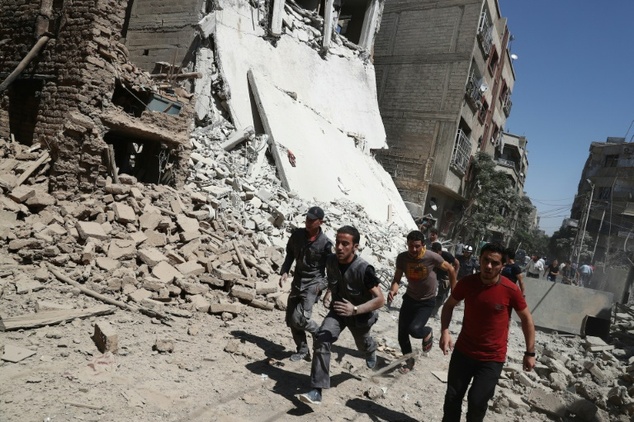 syrians run for cover during reported government air strikes in the rebel held town of douma east of the capital damascus photo afp