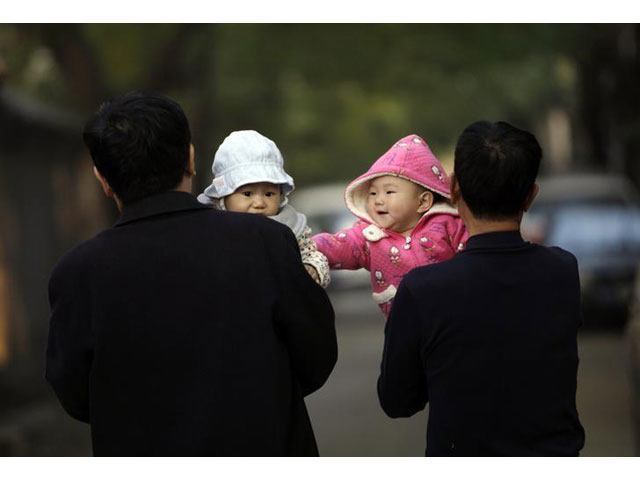 a 10 month old girl touches a boy as her grandfather carries her as they walk along a traditional alleyway or hutong in central beijing november 6 2012 photo reuters