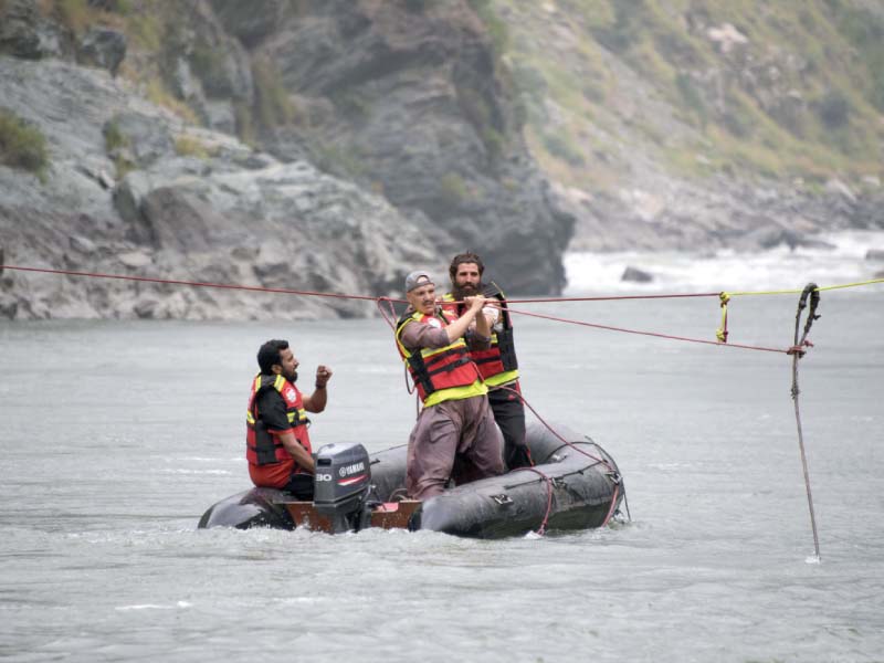 rescue workers use a rope in a bid to recover passengers that fell into a river neelum photo afp
