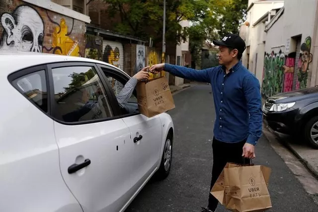 an uber driver takes delivery of bags of donuts destined for a customer via uber eats in sydney photo reuters an uber driver takes delivery of bags of donuts destined for a customer via uber eats in sydney photo reuters