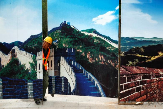 a worker looks through the fence of a construction site that is decorated with pictures of the great wall at badaling north of beijing china photo reuters a worker looks through the fence of a construction site that is decorated with pictures of the great wall at badaling north of beijing china photo reuters