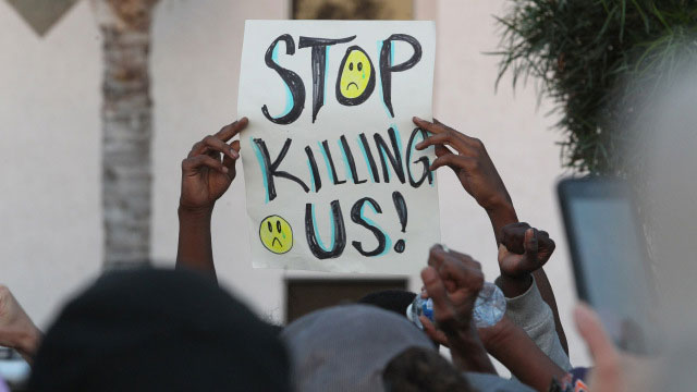 a man carries a sign during a protest in el cajon a suburb of san diego california on september 28 2016 in response to the police shooting the night before photo afp