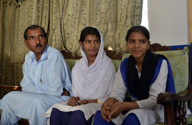 ashiq masih l the husband of asia bibi a pakistani christian mother sentenced to death in under blasphemy laws sits with daughters esham r and esha c at their residence in lahore on october 31 2014 photo afp