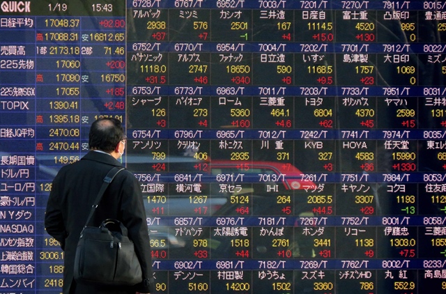 this file photo taken on january 19 2016 shows a pedestrian looking at a screen showing movements for the tokyo stock exchange in tokyo photo afp