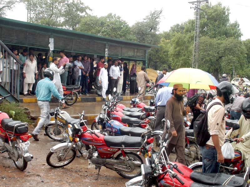 motorcyclists take shelter at shakrial bus stop during rain photo express