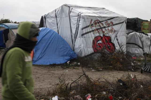 a migrants walks past a tent with a graffiti reading quot let 039 s go england quot in the quot new jungle quot makeshift camp as unseasonably cool temperatures arrive in calais northern france photo reuters