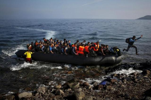 an afghan migrant jumps off an overcrowded raft onto a beach at a greek island photo reuters