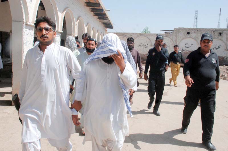 law enforcement personnel taking away a suspect after raiding a seminary in sukkur photo inp