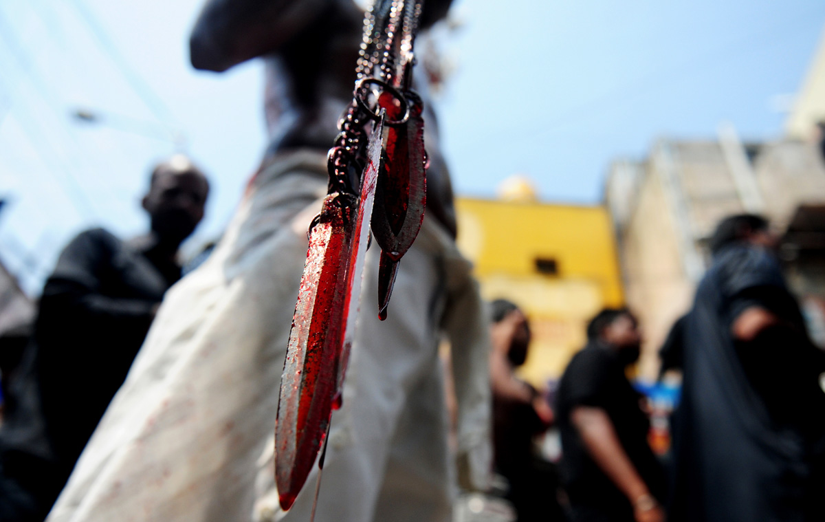 shia muslim man holds blood stained blades as he self flagellates during the mourning procession on the tenth day of muharram which marks the day of ashura photo afp