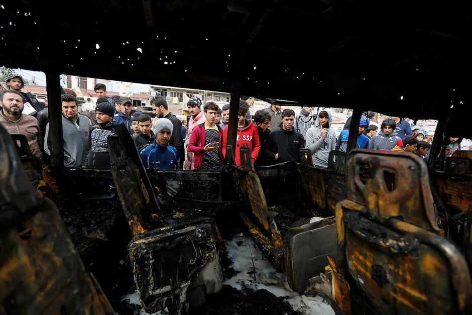 People look at a burned vehicle at the site of car bomb attack in a busy square at Baghdad's sprawling Sadr City district, in Iraq. PHOTO: REUTERS