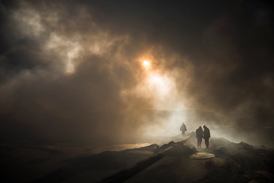 The sun cuts through the smoke as workers tasked with putting out the fire in an oil well, set ablaze by retreating Islamic State (IS) militants, assemble a water pipeline in the town of Qayyarah, some 70 km south of Mosul. PHOTO: AFP