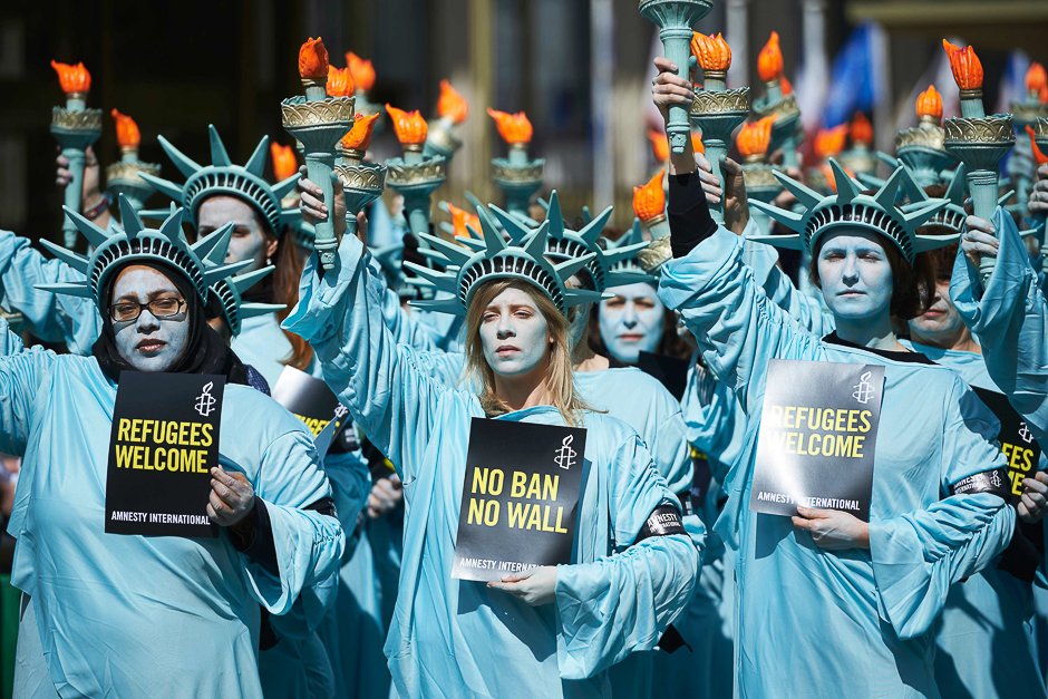 activists from amnesty dressed as the statue of liberty take part in a demonstration to mark the first 100 days in office of us president donald trump outside the us embassy in london photo afp