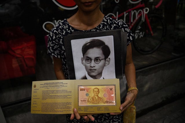 a thai woman poses with a commemorative 100 thai baht banknote bearing a picture of late king bhumibol adulyadej outside the government savings bank in bangkok on october 18 2016 photo afp