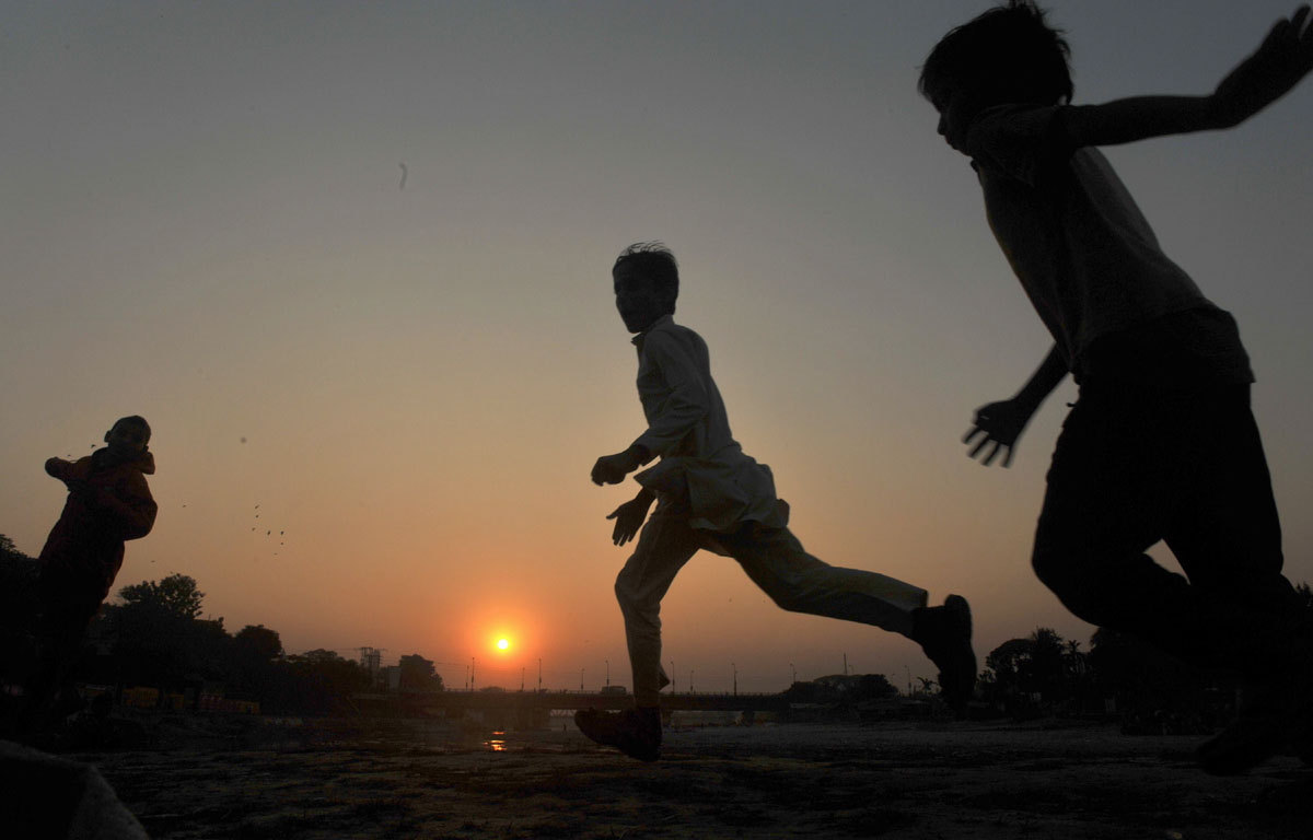 indian children run through a field as the sunsets in siliguri on december 31 2012 photo afp