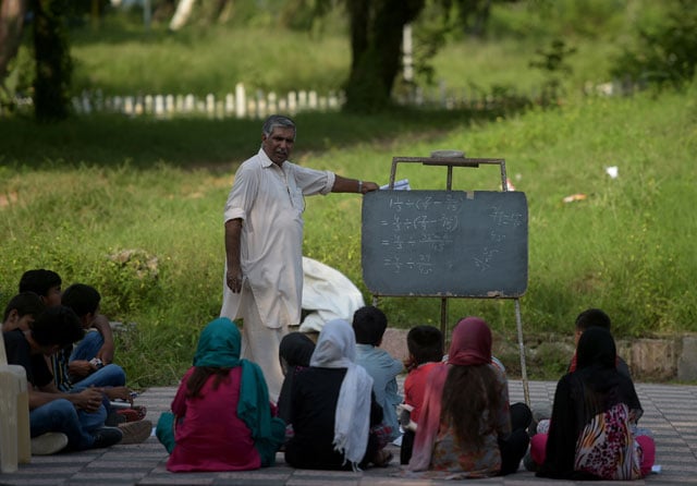 in this photograph taken on august 30 2016 muhammad ayub teaches pupils at a makeshift school in a park in islamabad photo afp