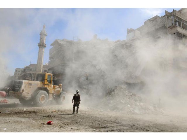 a civil defence member stands as a front loader removes debris after an air strike sunday in the rebel held besieged al qaterji neighbourhood of aleppo syria photo reuters