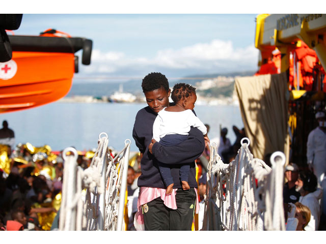 this handout picture taken and released by the italian red cross on october 22 2016 shows a woman and child walking up a gangplank as migrants land in vibo marina after a rescue operation in the mediterranean sea photo afp