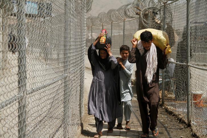 a family coming from afghanistan walk down a corridor between security fences at the border post in torkham pakistan june 18 2016 photo reuters