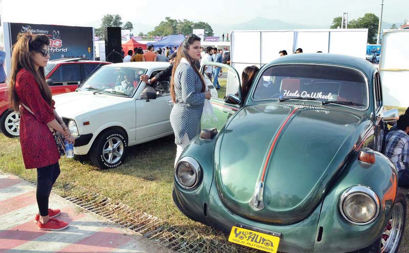 women look at vintage cars put on display at the auto show photo app