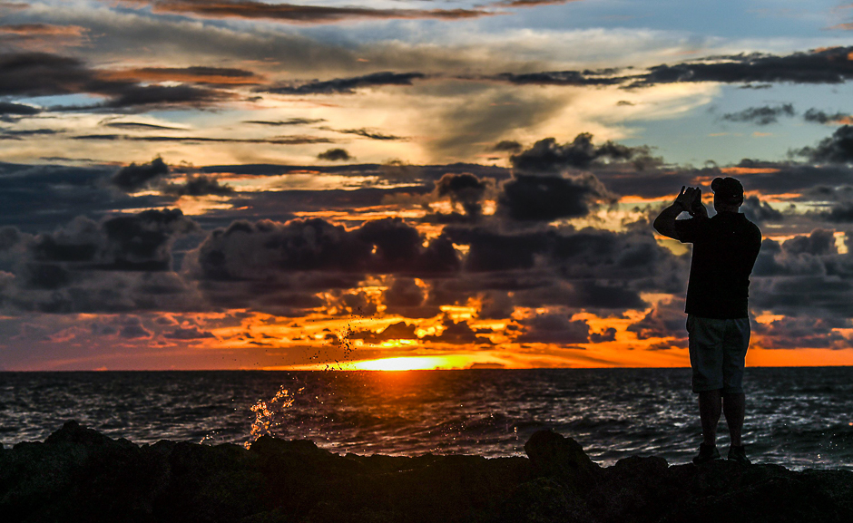 a tourist takes photos at sunset in cartagena colombia during the xxv ibero american summit photo afp